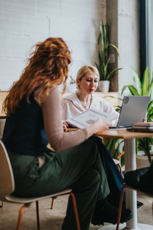 Two women discussing business strategies in a rustic co-working cafe spaceの写真素材