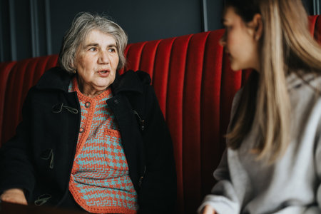 Elderly woman conversing with a younger person in a cozy indoor setting