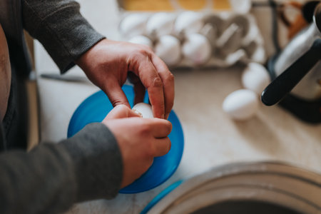 Hands preparing eggs for cooking in a kitchen setting, focusing on domestic chores and food preparationの写真素材