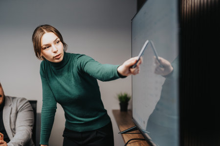 Businesswoman delivering a presentation to colleagues in a modern office environmentの写真素材