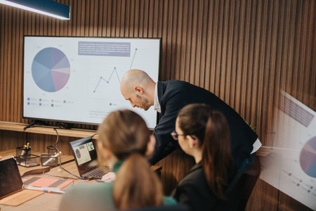 Business coworkers collaborating in a modern office setting with graphs displayedの写真素材