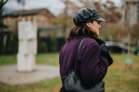 Woman exploring outdoors on a rainy day, dressed stylishly in purple coat and leather accessoriesの写真素材