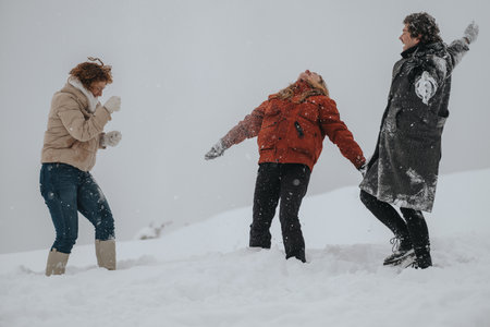 Friends playing joyfully in the snow and enjoying a winter day outdoorsの写真素材