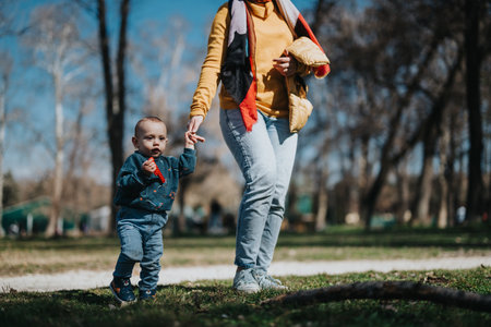 Parent walking with young child outdoors on a sunny dayの写真素材