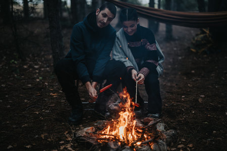 Couple Enjoying a Campfire in the Forest During a Cozy Winter Eveningの写真素材