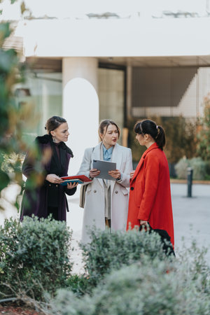 Professional Businesswomen Collaborating Outdoors in Modern Urban Settingの写真素材