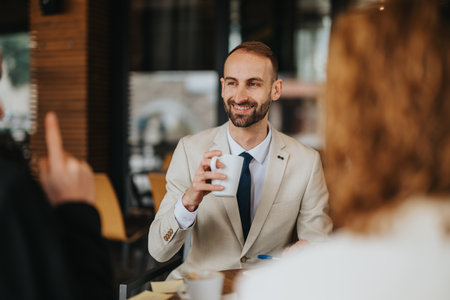 Smiling businessman having coffee with colleagues at an outdoor meetingの写真素材