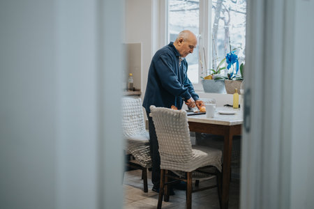 Senior man preparing vegetables in his kitchen with natural lightの写真素材