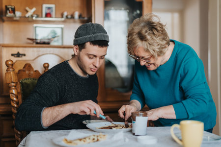 Senior woman enjoys cooking together with young man at the dining table