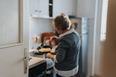 Senior woman cooking in a cozy kitchen with natural lightの写真素材