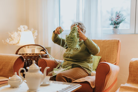 Senior woman enjoying knitting at home in a cozy and comfortable living spaceの写真素材