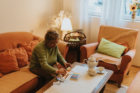 Senior woman arranging items on a table in a cozy living room spaceの写真素材