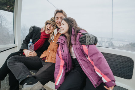 Three friends laughing and enjoying a winter outing together in a gondolaの写真素材