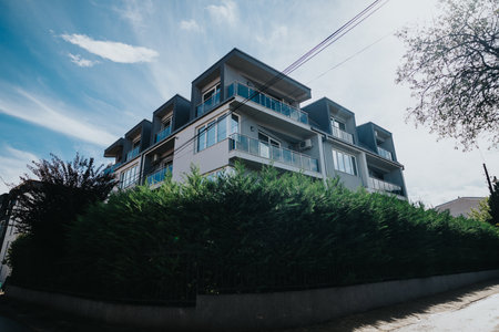 Modern apartment building surrounded by greenery under a bright blue skyの写真素材
