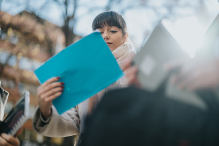 Young woman reviewing documents outdoors on a sunny dayの写真素材