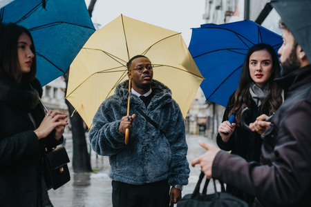 Group of Individuals with Umbrellas Engaging in a Conversation Outdoorsの写真素材