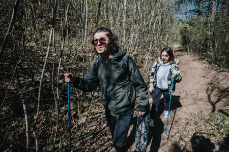 A couple hiking together through a forested nature trail on a sunny dayの写真素材