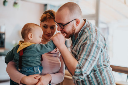 Happy family moments with parents bonding with their toddler child in a cozy home environmentの写真素材