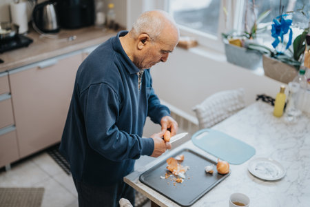 Elderly man peeling vegetables in his kitchen with natural light
