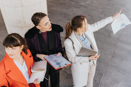 Group of professional women reviewing documents and discussing outdoorsの写真素材