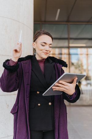 Businesswoman Using a Tablet and Stylus Outside an Office Buildingの写真素材