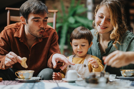 Happy parents enjoying breakfast together with their young child in a cozy home settingの写真素材