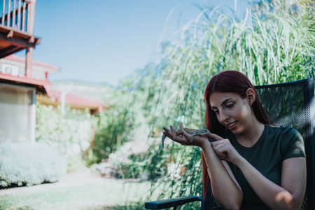 Young woman playing with a lizard outdoors, showcasing nature interaction and curiosity