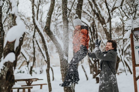Friends enjoying playful winter moments in a snowy outdoor parkの写真素材