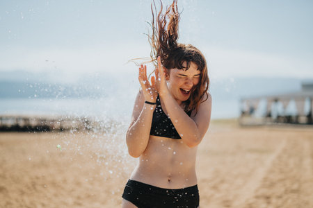 Young woman enjoying herself on a sunny beach with water splashesの写真素材
