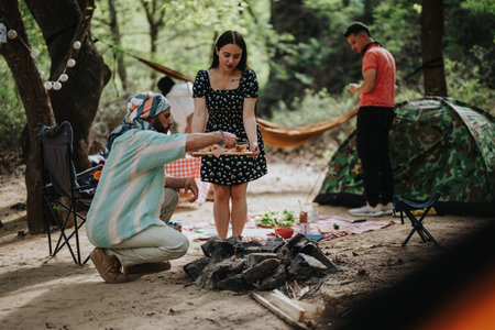 Friends enjoying a camping barbecue in a forested outdoor settingの写真素材