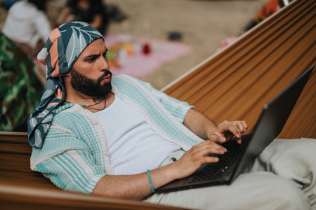 Man relaxing in a hammock while working on a laptop outdoorsの写真素材
