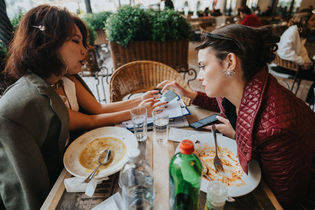 Two business women discussing ideas in a cafe setting outdoorsの写真素材