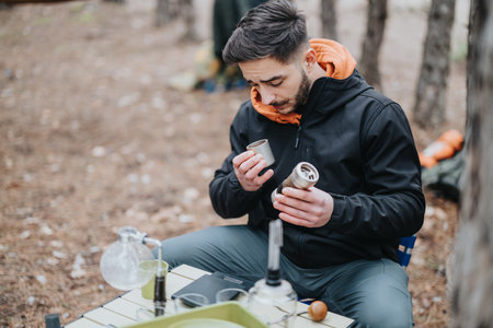 Man Preparing a Drink Outdoors During a Casual Winter Picnicの写真素材