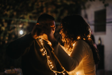 Romantic couple dancing at night wrapped in warm glowing string lightsの写真素材