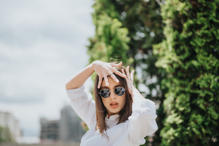 Stylish woman posing with sunglasses in an outdoor park settingの写真素材