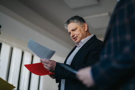 Businessman reviewing documents during a meeting in a corporate office settingの写真素材