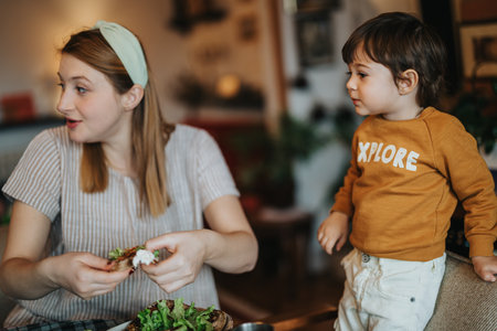 Mother and toddler enjoying a meal together in a cozy home environmentの写真素材