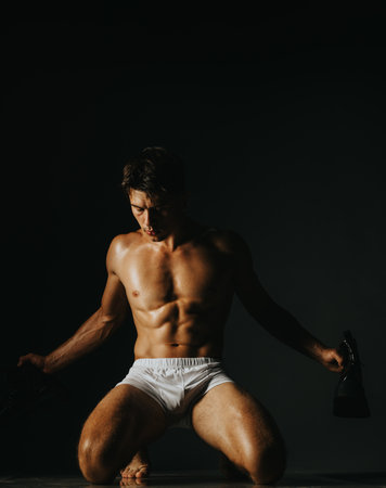 Athletic man posing shirtless in studio with dramatic lightingの写真素材
