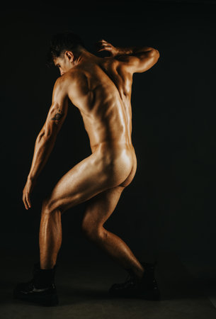 Artistic nude male posing in dramatic lighting on dark backgroundの写真素材