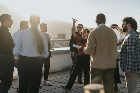 Diverse business colleagues gather on a rooftop terrace to celebrate success with music and dance during sunset.の写真素材