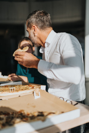 Business colleagues enjoying pizza lunch break in office settingの写真素材