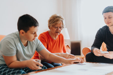Grandmother Playing Cards with Her Grandchildren in the Living Roomの写真素材