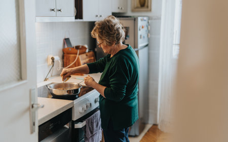 Elderly woman cooking in a cozy home kitchenの写真素材