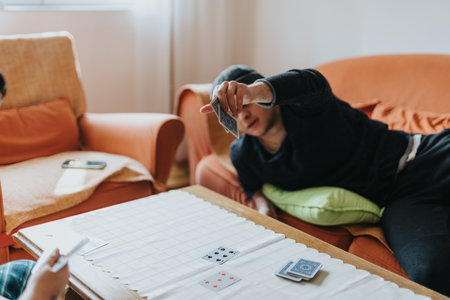 Two friends enjoying a game of cards in a cozy living room environmentの写真素材