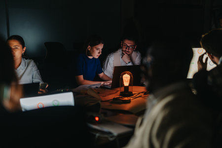 Diverse team collaborating in a dimly lit office late at nightの写真素材