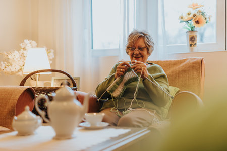 Senior woman knitting in cozy home interior with warm light and serene atmosphereの写真素材