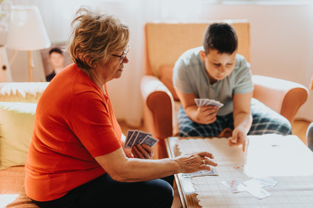Elderly woman and boy enjoy a game of cards together in a cozy living room settingの写真素材