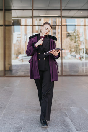 Confident Businesswoman Posing Outdoors With a Notebook in Stylish Attireの写真素材