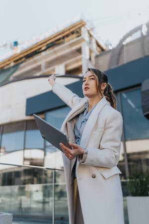 Confident businesswoman conducting construction consultation at a modern urban project.の写真素材