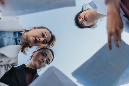 Three Professional Women Collaborating Outdoors on Documents During a Meetingの写真素材